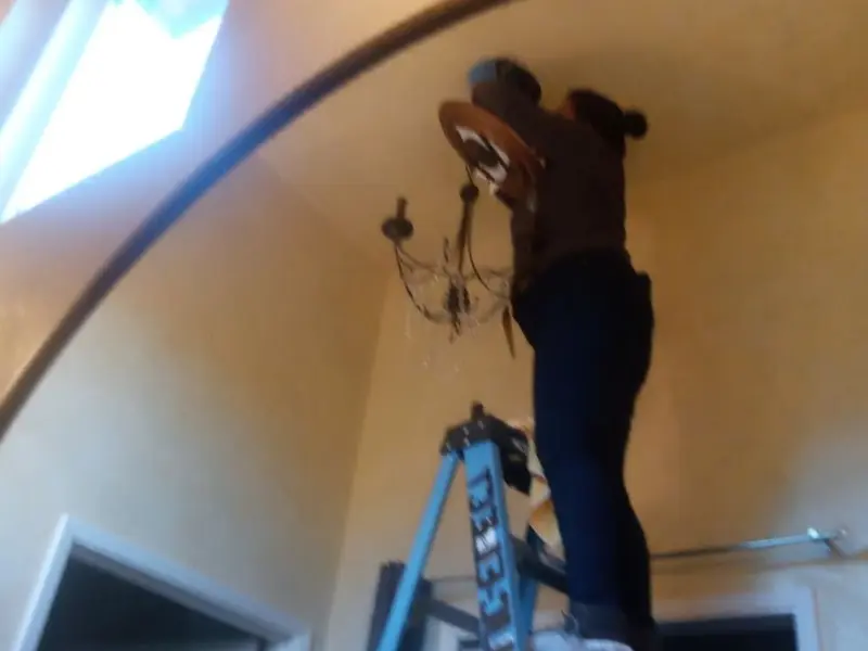 Electrician installing a chandelier in a Victor residence